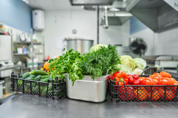 Fresh colorful Vegetables and fruit in kitchen on silver steel table. Work surface and kitchen equipment in professional kitchen.