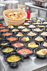Food delivery. Different in plastic disposable lunch box with healthy natural food. Chicken broth, mashed soup, mashed potatoes with cutlet, seafood pasta, salads, pilaf with a fresh bun.
