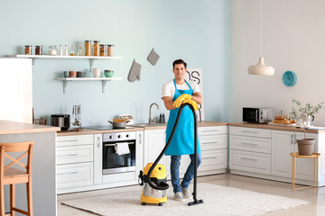 Young man with vacuum cleaner in kitchen