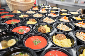 Food delivery. Different in plastic disposable lunch box with healthy natural food. Chicken broth, mashed soup, mashed potatoes with cutlet, seafood pasta, salads, pilaf with a fresh bun.