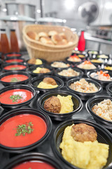 Food delivery. Different in plastic disposable lunch box with healthy natural food. Chicken broth, mashed soup, mashed potatoes with cutlet, seafood pasta, salads, pilaf with a fresh bun.