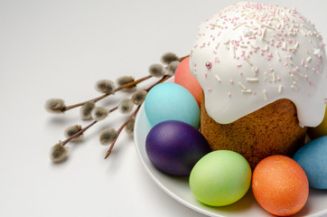 Kulich Easter cake with colored eggs with white glaze on white background