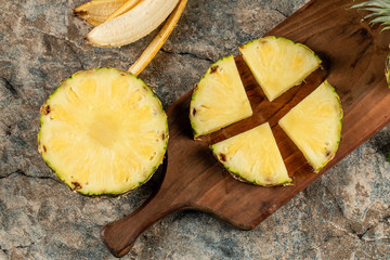 Pineapple slice cut into four pieces on a wooden board, top view