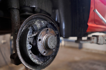 Rusty drum brakes, rear on red car. Change the old to new brake disc on car in a garage. Auto...