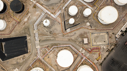 Aerial top down view on petroleum industrial factory, barrels, pipes, equipment parts at the sandy terrain creating an abstract forms and background.