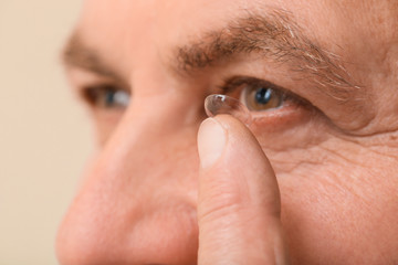 Mature man putting in contact lenses, closeup