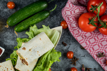 Fresh cherry tomatoes and cucumbers on the table with shaurma rolls