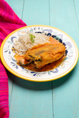 Mexican chili-stuffed poblano with rice on turquoise background