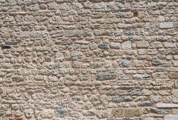 Old, brown, sandy, wall of a stone house in the open air. Seamless texture background rocks, bricks