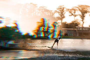 A double exposure of wakeboarder riding on a lake at sunset