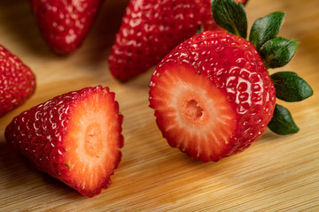 Red fresh strawberries cut into pieces on a wooden board