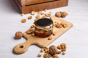 Jar of honey on a wooden board. Honey with nuts.