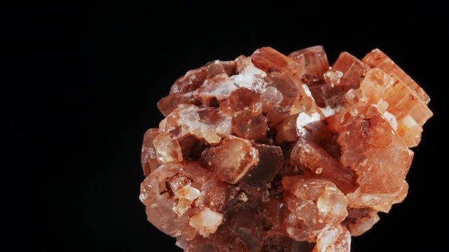 Seamlessly rotating a blood orange mineral Aragonite in front of black background