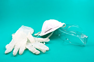 A mask, gloves and individual protection glasses for infections with possible viruses, on a green background