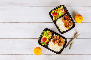 Ready meal to eat on food container with drink and orange.