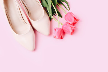 Female high-heeled shoe with beautiful tulips on pink background