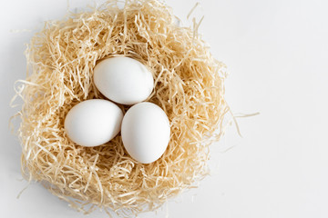 white chicken eggs in a nest on a white background, Easter eggs, place for text
