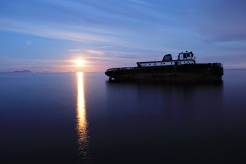 Barco hundido con amanecer de fondo 