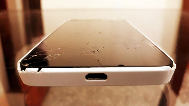Cell phone with white cover and broken screen