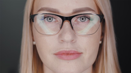 Fototapeta premium Attractive blonde hair business woman in glasses is looking at camera and smiles to show teeth braces standing at black background. Orthodontic treatment concept. Slowmotion closeup portrait 4K video