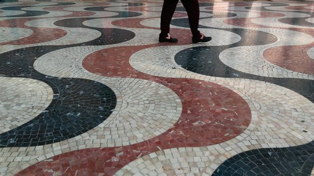  Detalle del Paseo de la Explanada en Alicante con su caracter&iacute;stico mosaico de teselas de colores  y pies de personas con ni&ntilde;os pasando 