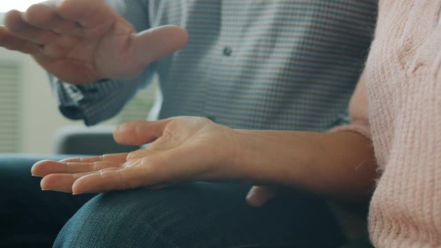 Close-up of elderly man and woman holding hands expressing love and care indoors. Loving relationship, senior people and happiness and commitment concept.