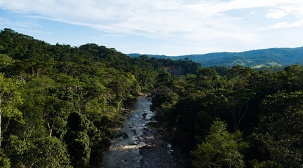 Fototapeta na wymiar Aerial view on a river crossing the amazon rainforest in the Peruvian jungle. Stones in the river, green trees, blue sky, full vegetation. 