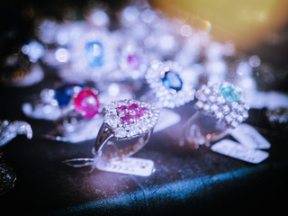 Defocused view of jewelry store with focus on the ring with magenta gem stones for sale as seen in Spanish showcase fashion store