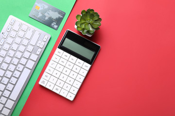 Calculator with credit card and computer keyboard on color background