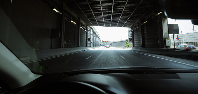 Paris, France - Jun 14, 2018: Wide image view of driver POV personal perspective including the steering wheel part and the front driving cars exiting the tunnel of Boulevard peripherique