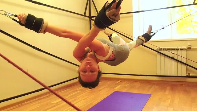 Sporty young caucasian woman doing stretching exercises of full body muscles workout on stretch aerobic aero strap in gym,yogi mat