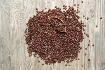 Many coffee beans with cacao pod on wooden background