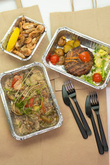 Paper bag meat and steak in their foil containers on an isolated white background. The view from the top,