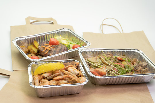 Lunch and dinner with home delivery in foil boxes and paper bag on a white background.