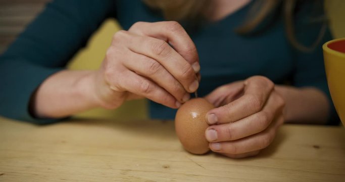 Young woman piercing an egg for blowing out and decorating