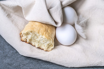 rustic breakfast or a snack with homemade bread and fresh eggs only from chicken in a linen eco bag. macro view and close up on gray stone background