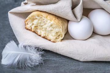 rustic breakfast or a snack with homemade bread and fresh eggs only from chicken in a linen eco bag. macro view and close up on gray stone background