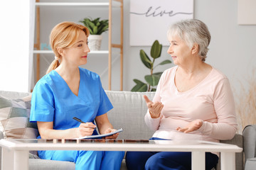 Obraz premium Elderly woman suffering from mental disability and caregiver in nursing home
