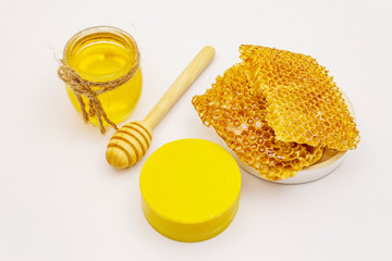 Honey, beeswax and wooden honey dipper isolated on white background