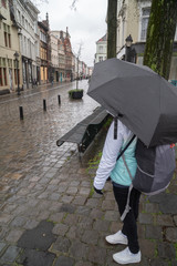 Girl in the rain under umbrella. Protection from rain. Selective focus