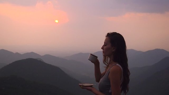beautiful girl enjoy the organic fresh coffee or masala chai in india hills with top nice view at evening sunset