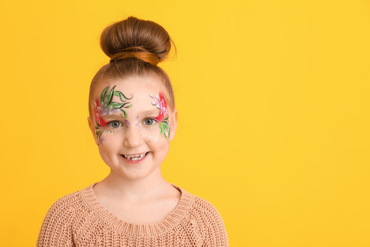 Funny little girl with face painting on color background