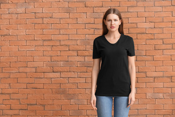 Young woman in stylish t-shirt on brick background