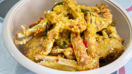 Close up view of buttermilk crab mixed with salted duck eggs in a white bowl.