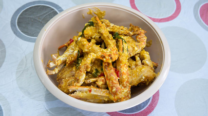 Close up view of buttermilk crab mixed with salted duck eggs in a white bowl.