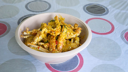 Close up view of buttermilk crab mixed with salted duck eggs in a white bowl.