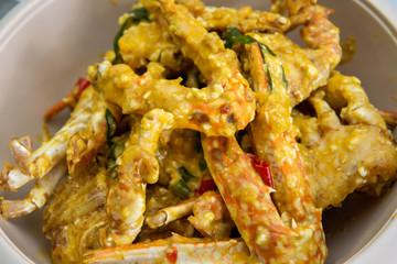 Close up view of buttermilk crab mixed with salted duck eggs in a white bowl.