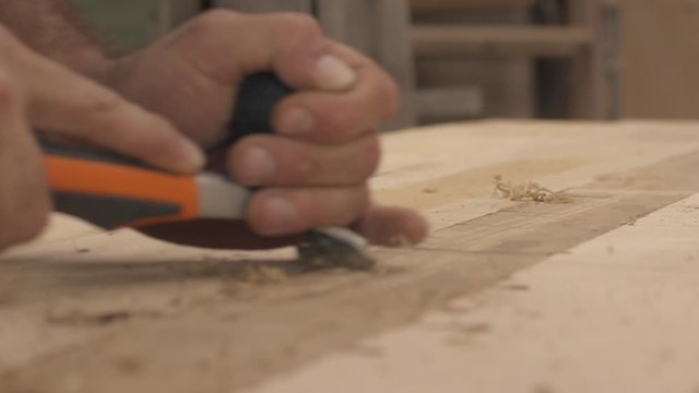 Low angle slow motion close up of a carpenter using a planer on wood boards in his shop