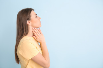 Young woman checking thyroid gland on color background