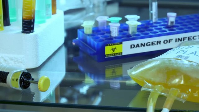 Scene tracks right past test tubes and vials to an IV bag of blood plasma for possible treatment of COVID19.